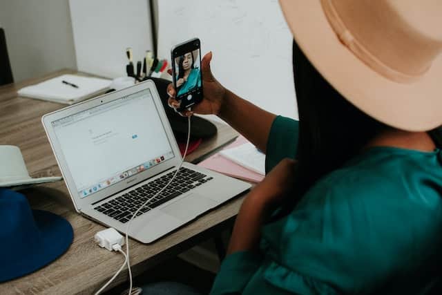 Black woman on her laptop and looking at her phone.